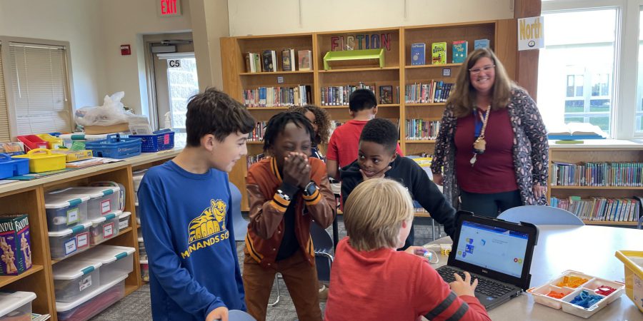 students smiling and cheering around a computer