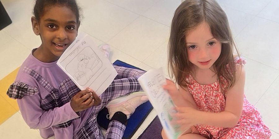 Summer learning - two students sit on a floor holding books