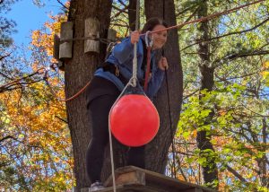 Student smiles standing high in the air on a rope