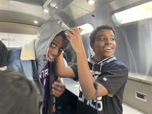 one student puts a microscope against another student's hair to see what it looks like on a large screen