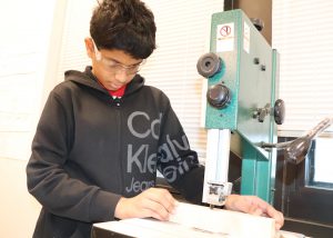 student cutting wood