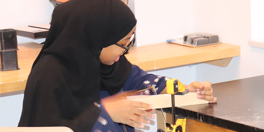 A student cuts a piece of wood for a technology project.
