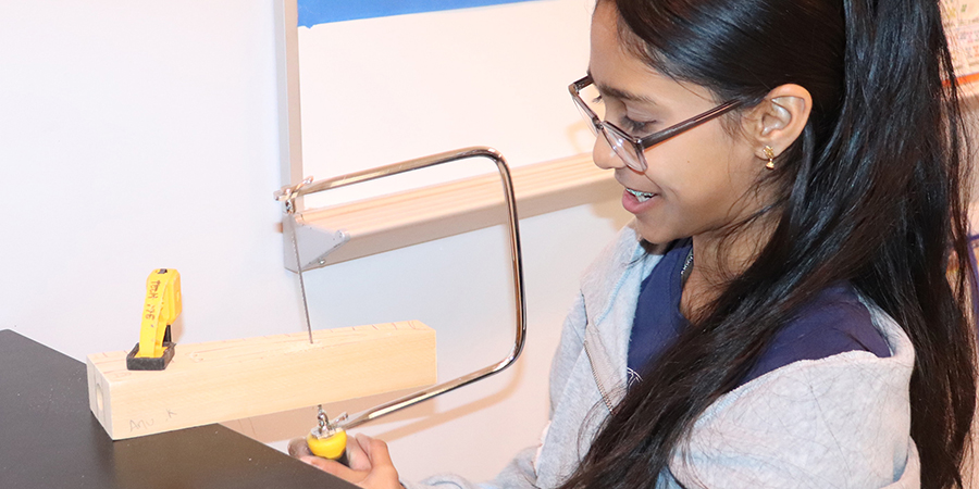 AnuKannan_Gr8_Technology2_900x450px A girl cuts wood and smiles