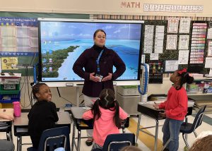 A counselor poses in front of a class of students