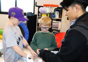 MEnands students play with a gadget as a college student helos
