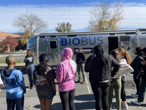 students standing outside a bus equipped to do science experiments