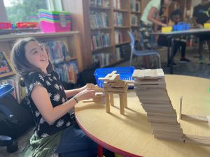 student laughing as she builds sculptures out of wood pieces