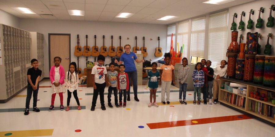 students standing togetherin a music room with guitars behind them