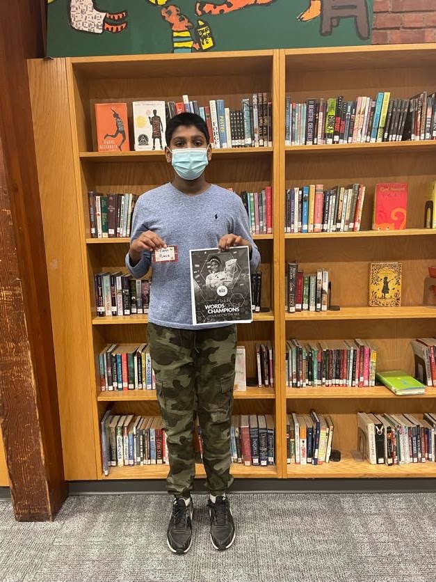 Spelling bee winner standing in front of a book case