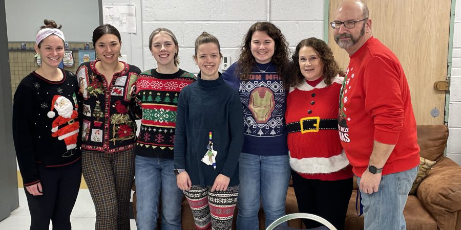 seven staff members wearing holiday sweaters