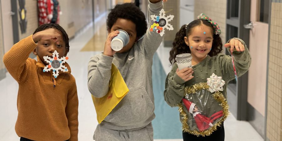 three students holding up ornaments they made