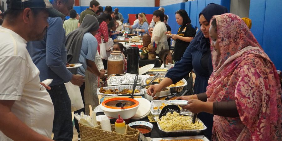 people line up at tables to put food on their plates