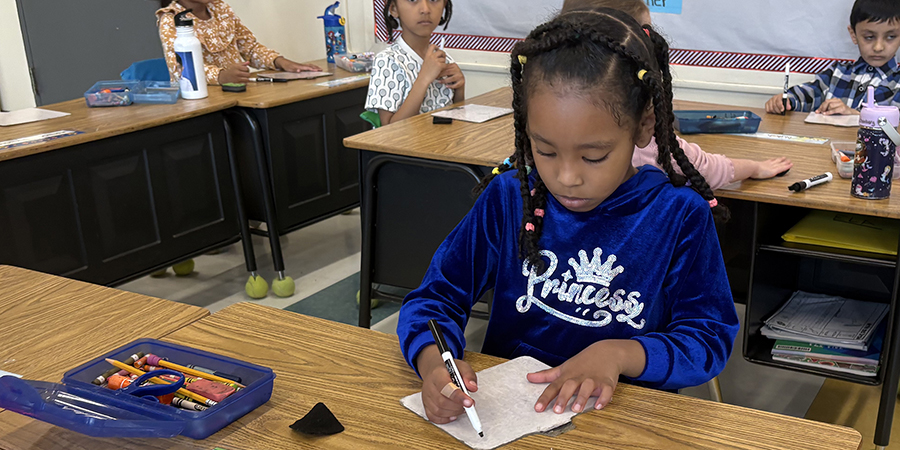 A second grade student is hard at work in class.