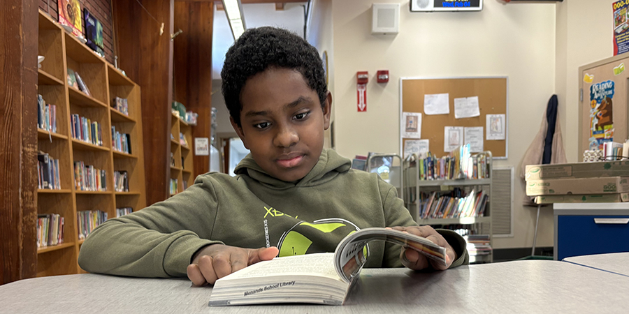 Student reads a book at a desk