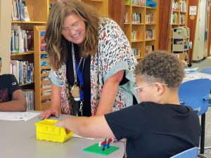 students building with Legos and teacher smiling at him