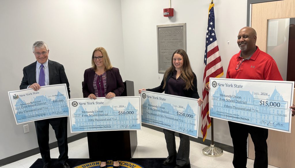 Officials hold large checks 