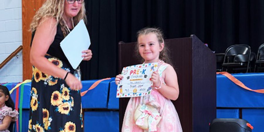 A PreK student smiles during her moving-up ceremony