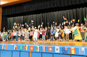 students on stage holding flags of different countries