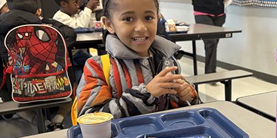 A student smiles while eating breakfast
