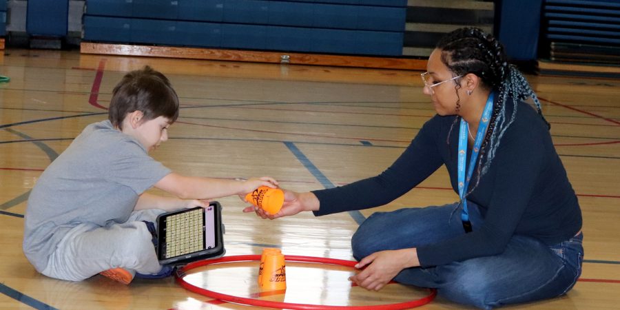 A student and aid sit in the gym