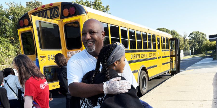 Father hugs daughter in front of bus