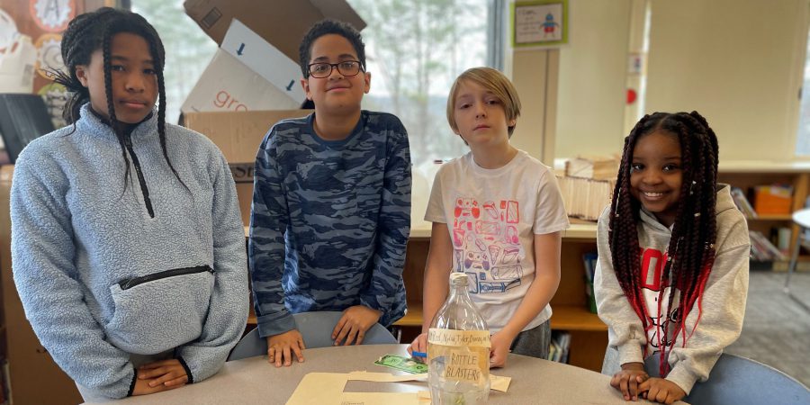 students standing around a table with a plant experiment