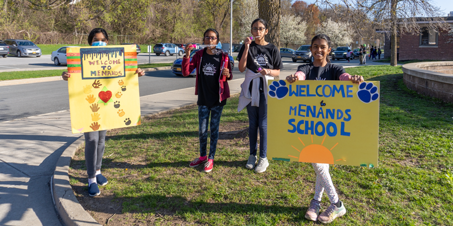 four students outside holding signs